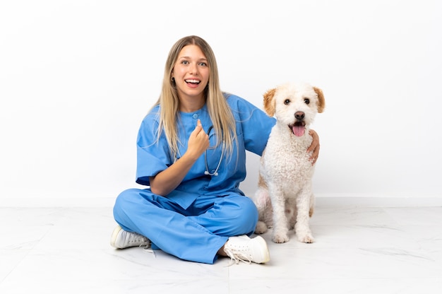 Jeune femme vétérinaire avec chien assis sur le sol avec une expression faciale surprise