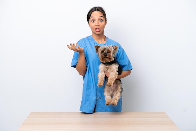 Jeune femme vétérinaire avec chien sur une table isolée sur fond blanc avec une expression faciale choquée