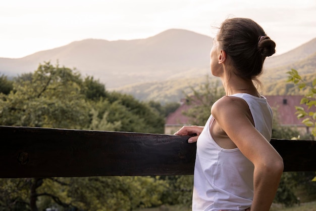 Photo une jeune femme vêtue d'un débardeur blanc profite d'un magnifique paysage naturel avec vue sur la montagne