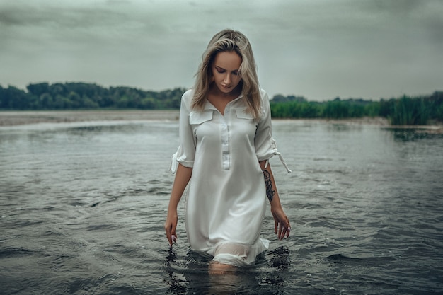 Jeune femme vêtue d'une robe pose dans une eau