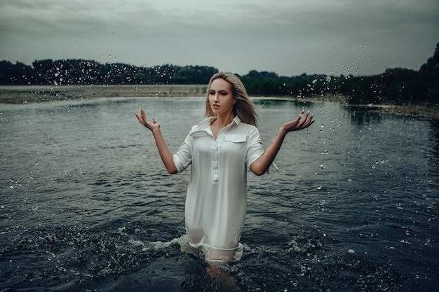 Jeune femme vêtue d'une robe pose dans une eau