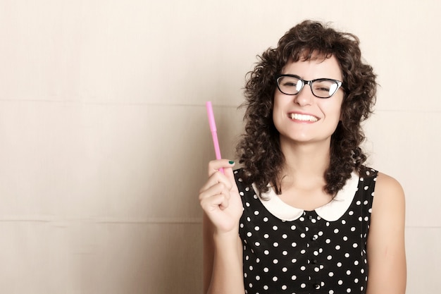 Une jeune femme vêtue d'une robe vintage tenant un stylo.