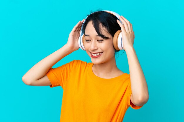 Jeune femme vietnamienne isolée sur fond bleu, écouter de la musique