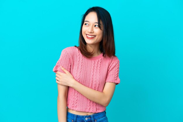 Jeune femme vietnamienne isolée sur fond bleu en riant