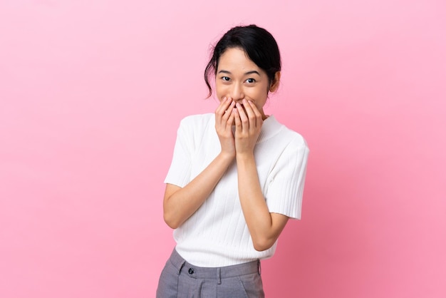 Jeune femme vietnamienne isolée sur fond rose heureuse et souriante couvrant la bouche avec les mains