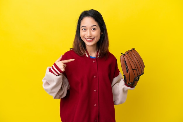 Jeune femme vietnamienne de joueur avec le gant de base-ball d'isolement sur le fond jaune donnant un geste du pouce levé