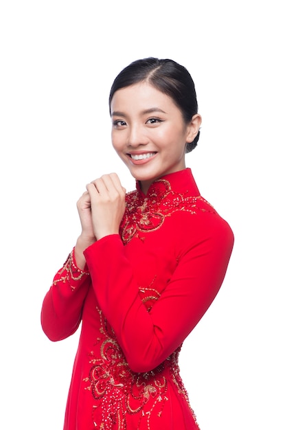 Jeune femme vietnamienne en robe Ao Dai avec un geste de prière vous souhaitant bonne chance