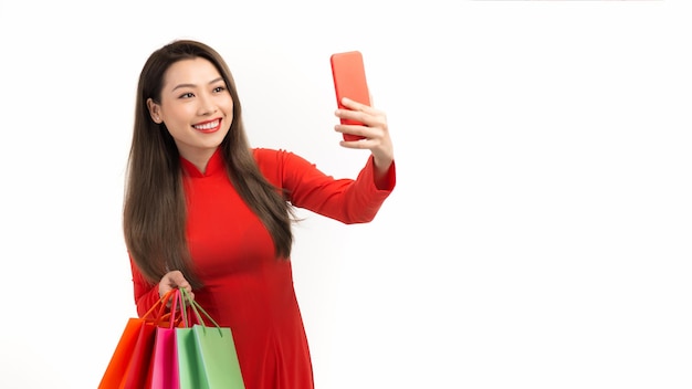 Jeune femme vietnamienne tenant des sacs à provisions et un téléphone intelligent