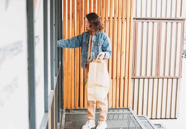 Jeune femme avec de vieux vêtements au point de réception des matériaux pour le recyclage