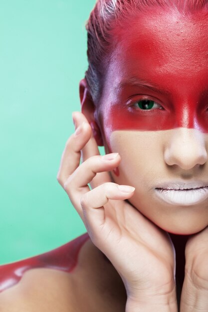 Jeune femme avec visage-art créatif sur fond vert