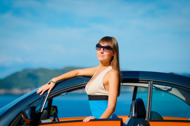 Jeune femme avec voiture au bord de la mer