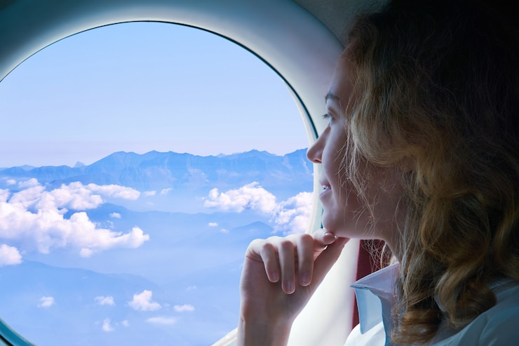 Photo la jeune femme vole dans un avion regardant par le hublot aux montagnes ci-dessous
