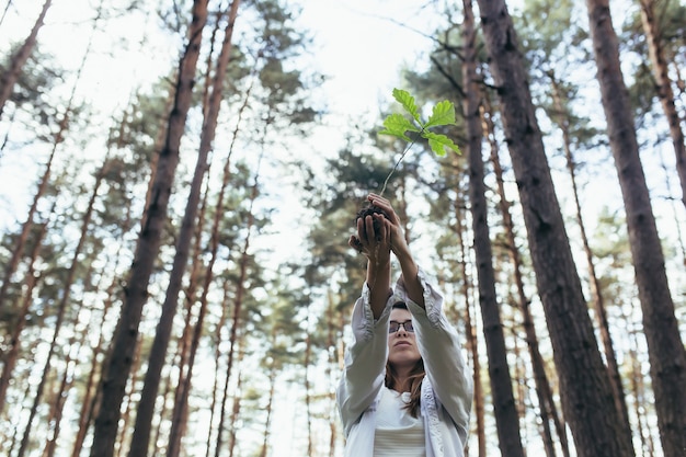 Une jeune femme volontaire plante une forêt, tenant un semis de chêne dans ses mains