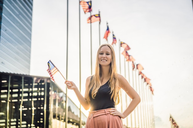 La jeune femme voyage en Malaisie tient le drapeau malaisien