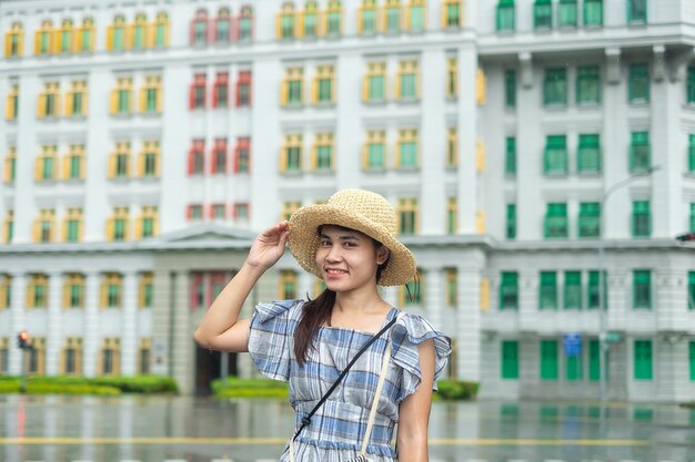 Jeune femme voyageant avec un chapeau, visite du voyageur asiatique heureux au bâtiment coloré arc-en-ciel à Clarke Quay, Singapour. point de repère et populaire pour les attractions touristiques. Concept de voyage en Asie