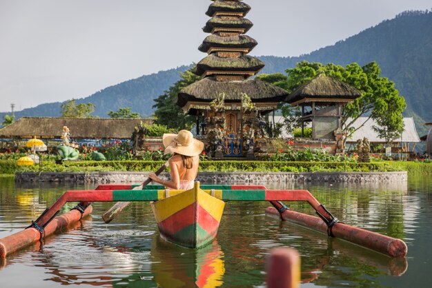 Jeune Femme Voyageur Pagayant Sur Un Bateau En Bois à Pura Ulun Danu Bratan