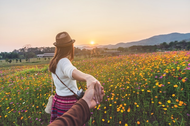 Jeune femme voyageur tenant la main de l&#39;homme et le conduisant sur le champ de fleurs