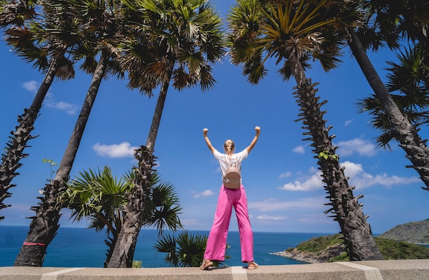 Jeune femme voyageuse en vacances d'été avec de beaux palmiers et des paysages marins