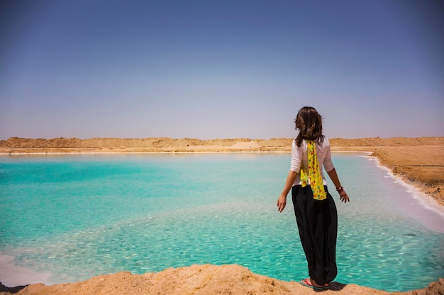 Jeune femme vue arrière, méconnaissable sur la rive du lac salé dans l'oasis de Siwa, lac salé