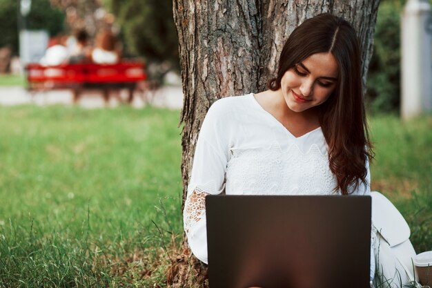 Jeune femme a le week-end et s'assoit dans le parc pendant la journée