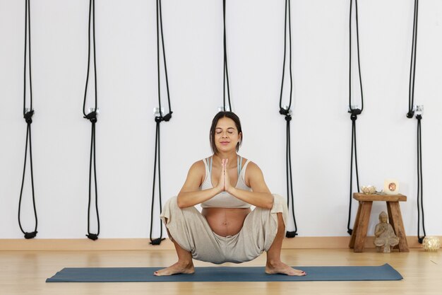 La jeune femme de yoga de grossesse pratique le yoga à la maison