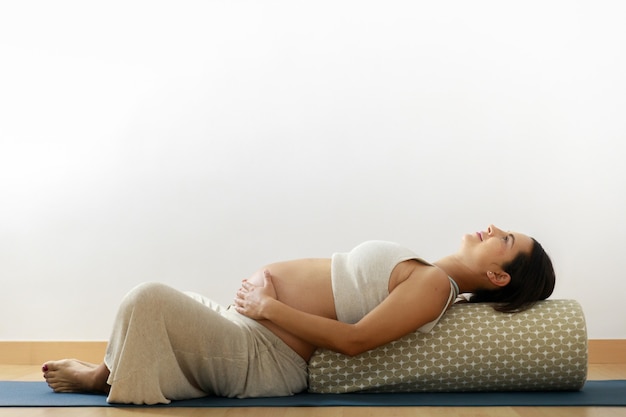 La jeune femme de yoga de grossesse pratique le yoga à la maison