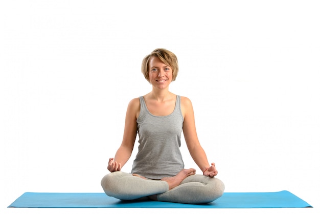 Jeune femme de yoga méditant en position du lotus. Isolé sur mur blanc