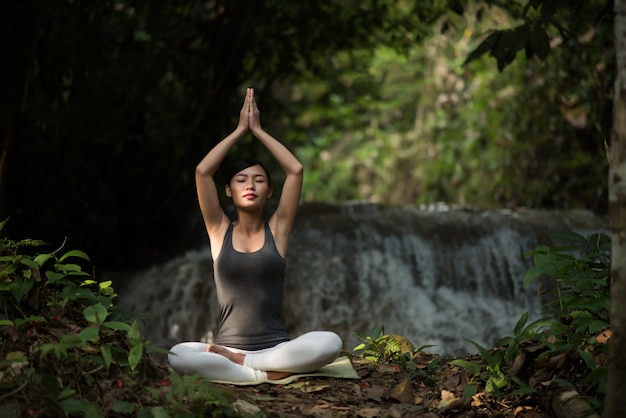 Jeune femme en yoga pose assis près de cascade