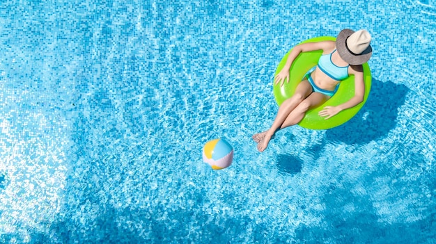 Jeune fille active dans la piscine vue aérienne de dessus d'en haut l'adolescent se détend et nage sur l'anneau