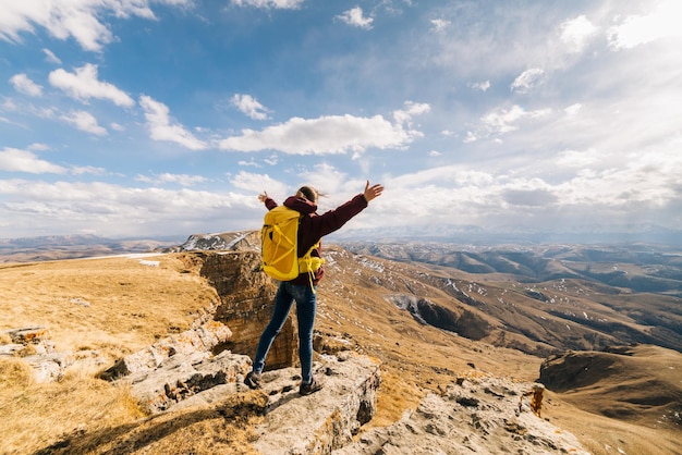 Une jeune fille active parcourt les montagnes du Caucase, avec un sac à dos jaune, profite du soleil