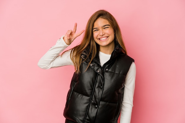 Jeune fille adolescente caucasienne maigre joyeuse et insouciante montrant un symbole de paix avec les doigts.