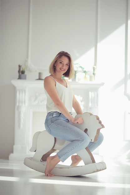 jeune fille adulte sur un cheval à bascule / photo insolite d'une fille dans le studio rire drôle