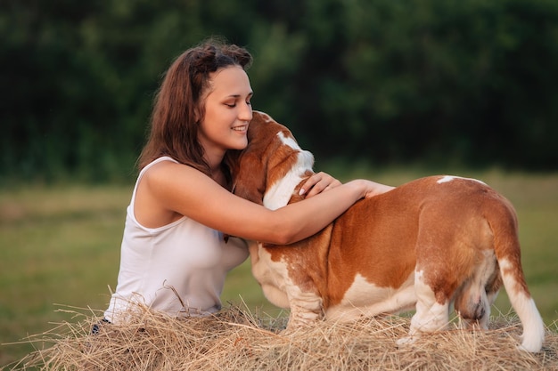 Une jeune fille adulte se promène avec un chien Basset Hound dans la nature Le propriétaire embrasse l'animal