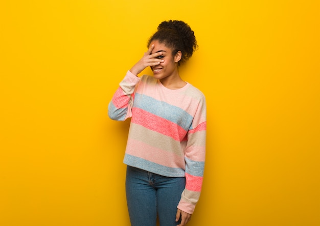 Photo jeune fille afro-américaine noire aux yeux bleus embarrassée et riant en même temps