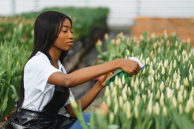 Jeune fille afro-américaine, ouvrière avec des fleurs en serre.