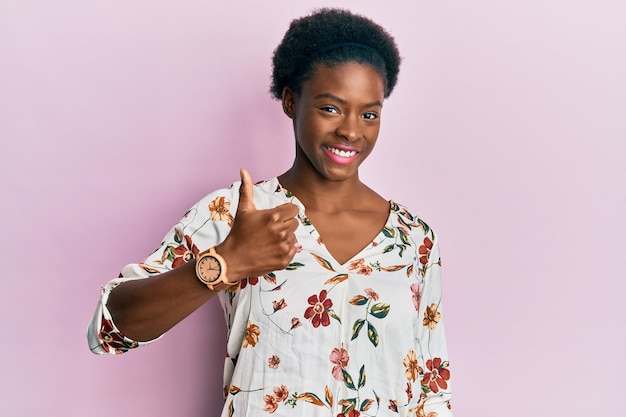 Jeune fille afro-américaine portant des vêtements décontractés faisant un geste heureux avec la main. approuvant l'expression en regardant la caméra montrant le succès.