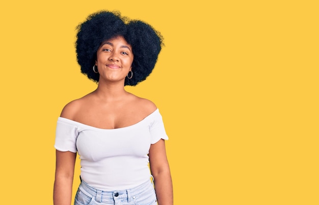 Jeune fille afro-américaine portant des vêtements décontractés à la recherche positive et heureuse debout et souriant avec un sourire confiant montrant les dents