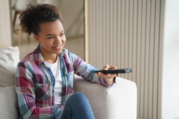 Jeune fille afro-américaine regardant un film ou une série télévisée en profitant d'un programme télévisé à la maison