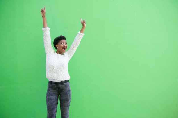 Jeune fille afro-américaine souriante contre le mur vert