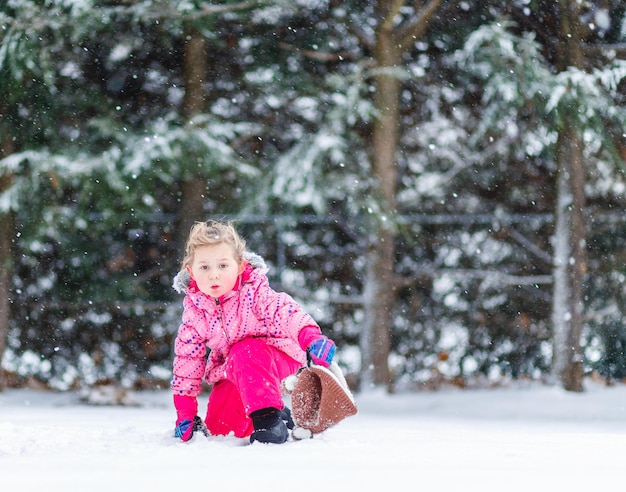 Une jeune fille agenouillée dans une tempête de neige pendant des rafales de lumière en hiver