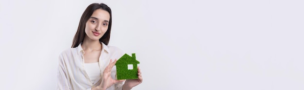Une jeune fille agent immobilier tient un modèle de maison verte dans ses mains Vente de biens immobiliers écologiques