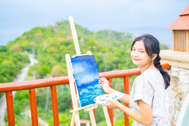 Jeune fille à l'aide d'une image de dessin au pinceau sur papier de toile à la belle vue sur le paysage à koh tao Thaïlande