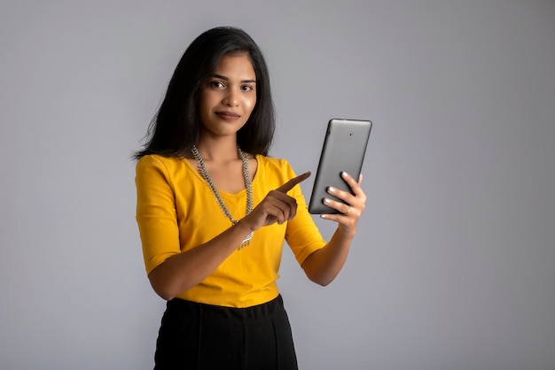 Jeune fille à l'aide de téléphone mobile ou smartphone sur mur gris