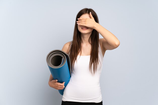 Jeune fille allant à des cours de yoga tout en tenant un tapis couvrant les yeux par les mains