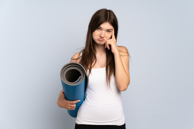 Jeune fille allant à des cours de yoga tout en tenant un tapis pensant une idée