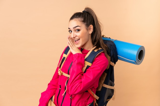 Jeune fille alpiniste avec un grand routard sur mur beige chuchoter quelque chose