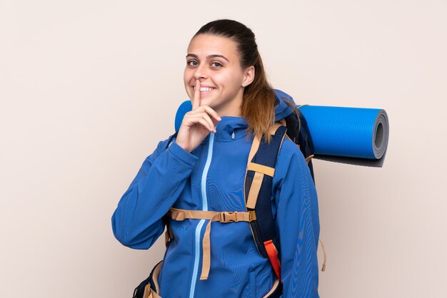 Jeune fille d'alpiniste avec un gros sac à dos faisant le geste de silence