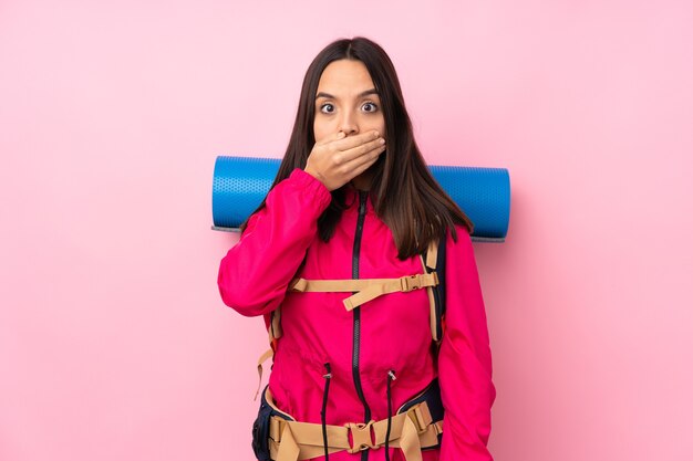 Jeune fille d'alpiniste avec un gros sac à dos rose isolé couvrant la bouche avec les mains