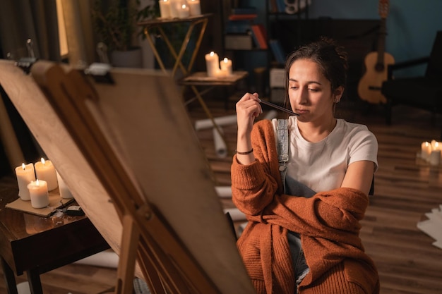 Une jeune fille avec une âme artistique regarde pensivement une peinture un dessin