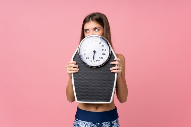 Jeune fille avec appareil de pesage sur rose isolé